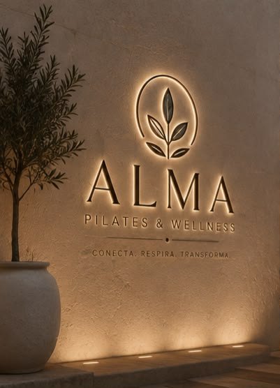 Muro de ALMA con el logo iluminado y un olivo